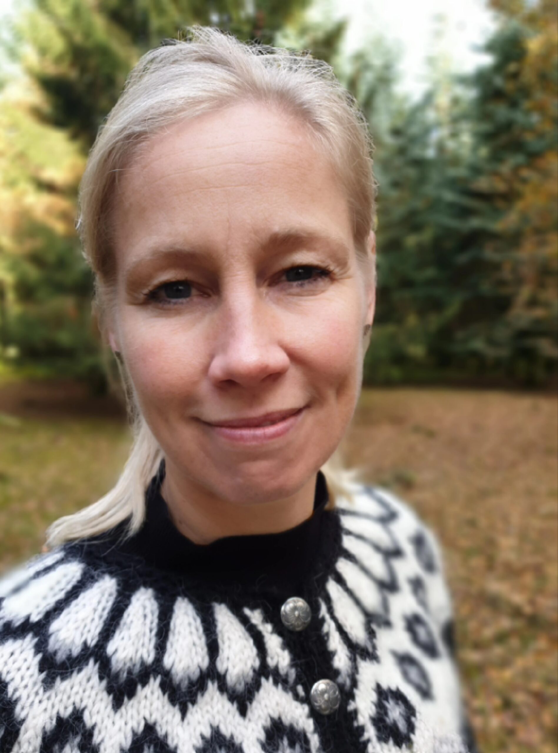 Ergoterapeut Anja Larsen sidder på en bænk under et træ med arbejdspapir i hånden